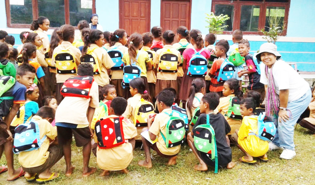 Esther with children showing their new backpacks.