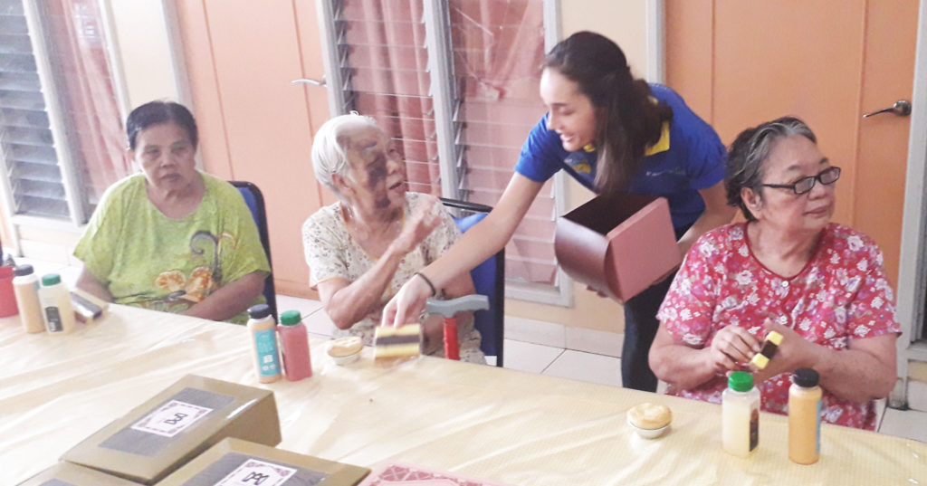 Bella helps to pass out the food and drinks to the elderly